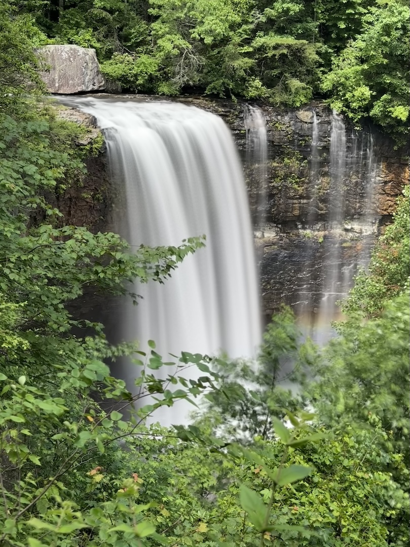Lula Falls viewed through the trees with rainbow at the base